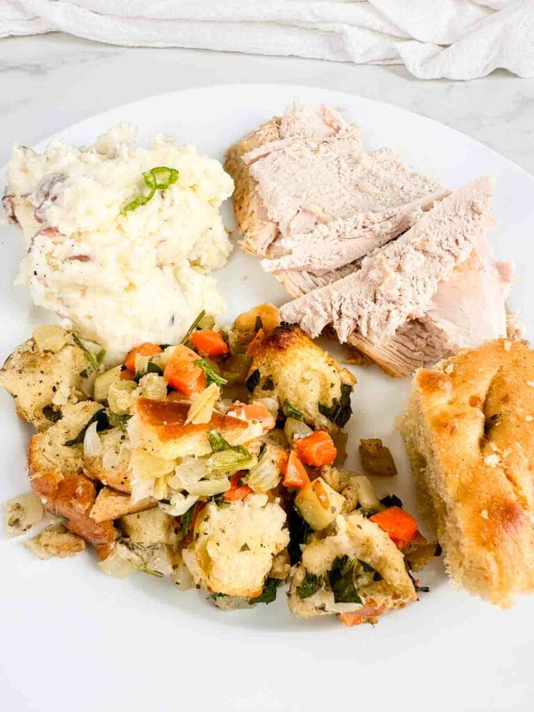 Plate of mashed potatoes, turkey, sourdough stuffing, and corn bread.