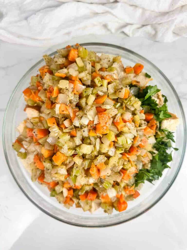 Sauteed carrots, onions, and celery, parsley, and sourdough in a bowl.