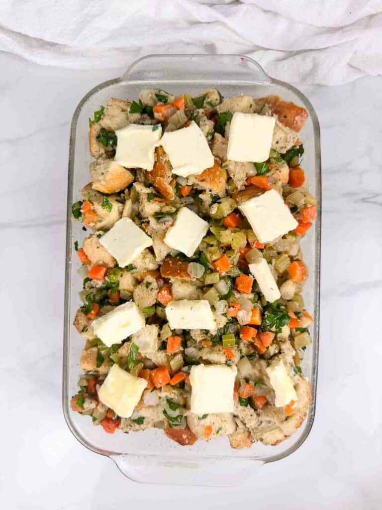 Pads of butter on top of unbaked sourdough stuffing.