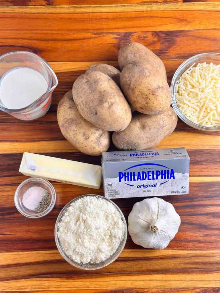 Ingredients for cheesy mashed potatoes: cream, potatoes, cheddar cheese, butter, cream cheese, parmesan cheese, garlic, salt, and pepper.