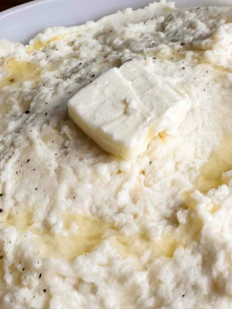 Cheesy mashed potatoes with freshly cracked black pepper and butter.