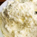 Cheesy mashed potatoes with freshly cracked black pepper.
