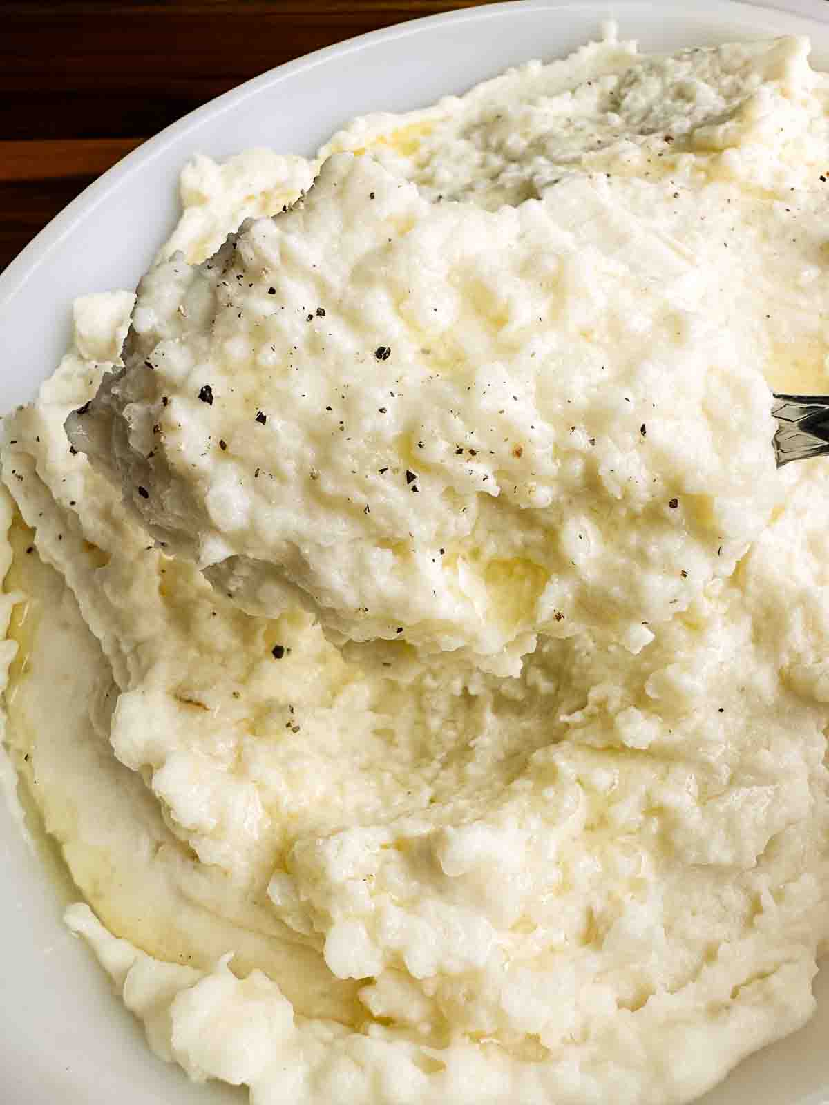 Cheesy mashed potatoes with freshly cracked black pepper.