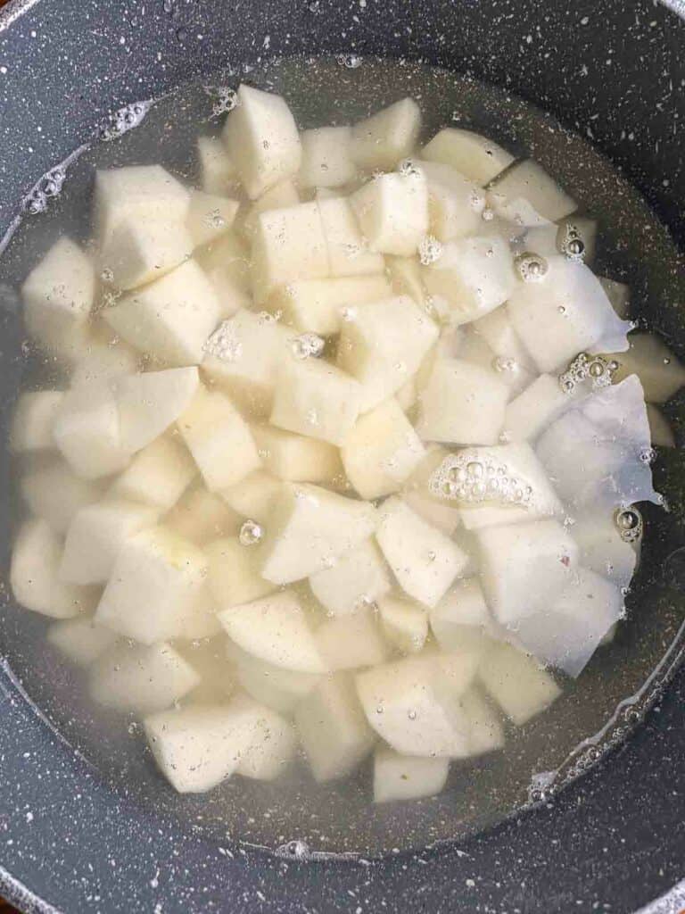 Add cool water to a pot with potatoes to start the process of making mashed potatoes.