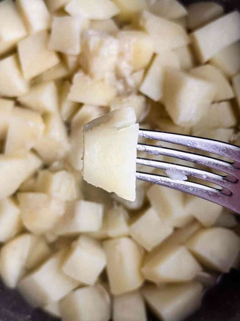 Cooking potatoes until they are fork tender.