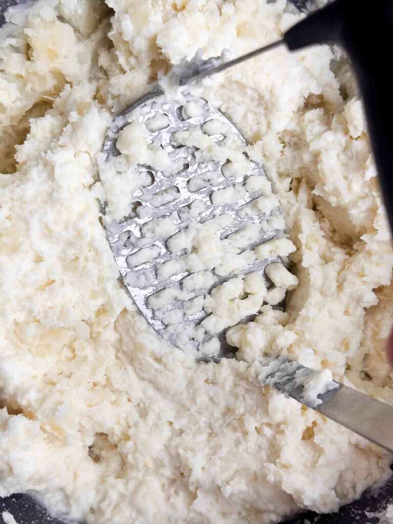 Mashing cheesy mashed potatoes.