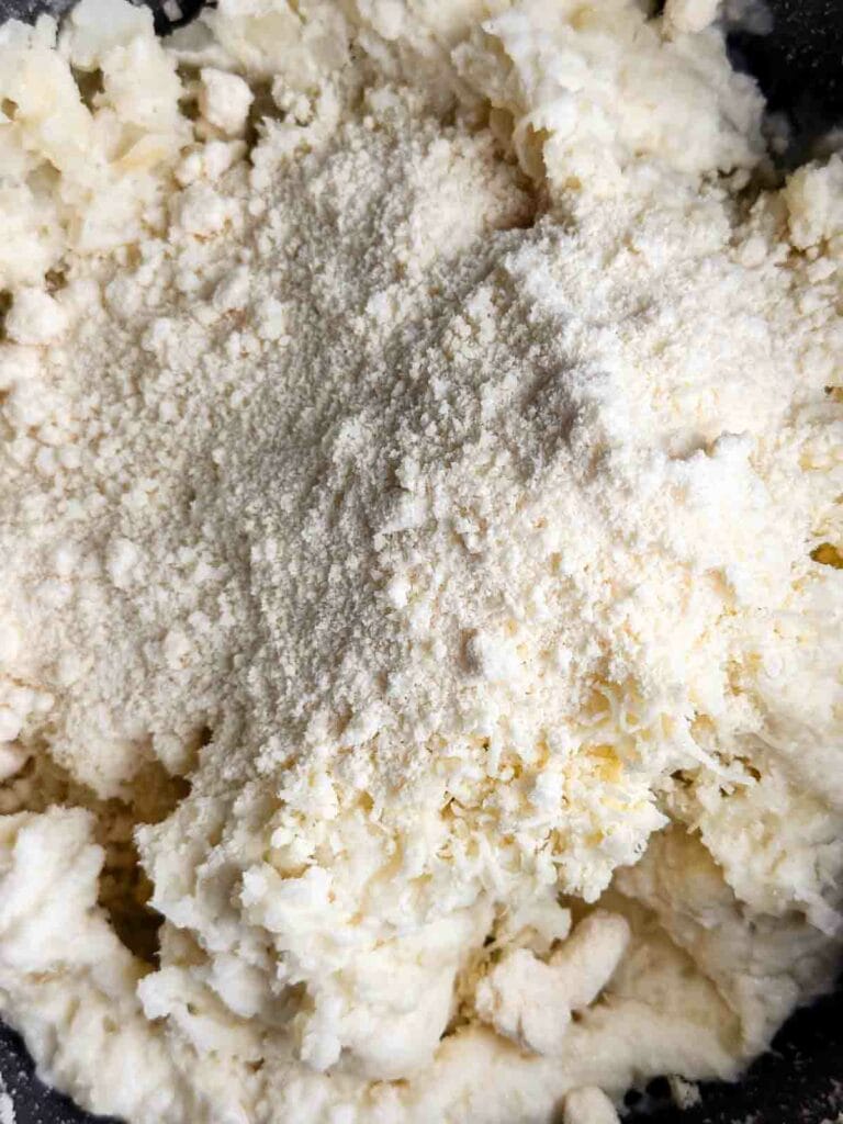 Adding in parmesan cheese to cheesy mashed potatoes.