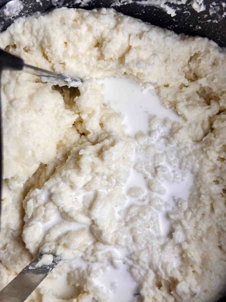 Adding cream to mashed potatoes to increase the moisture level.
