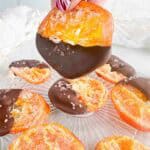 Chocolate dipped orange slices with one held above the others.