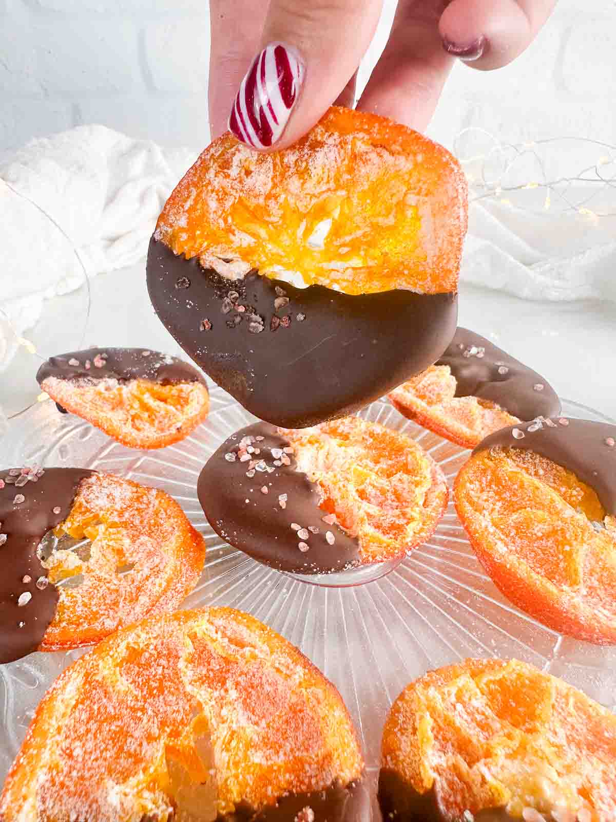 Chocolate dipped orange slices with one held above the others.