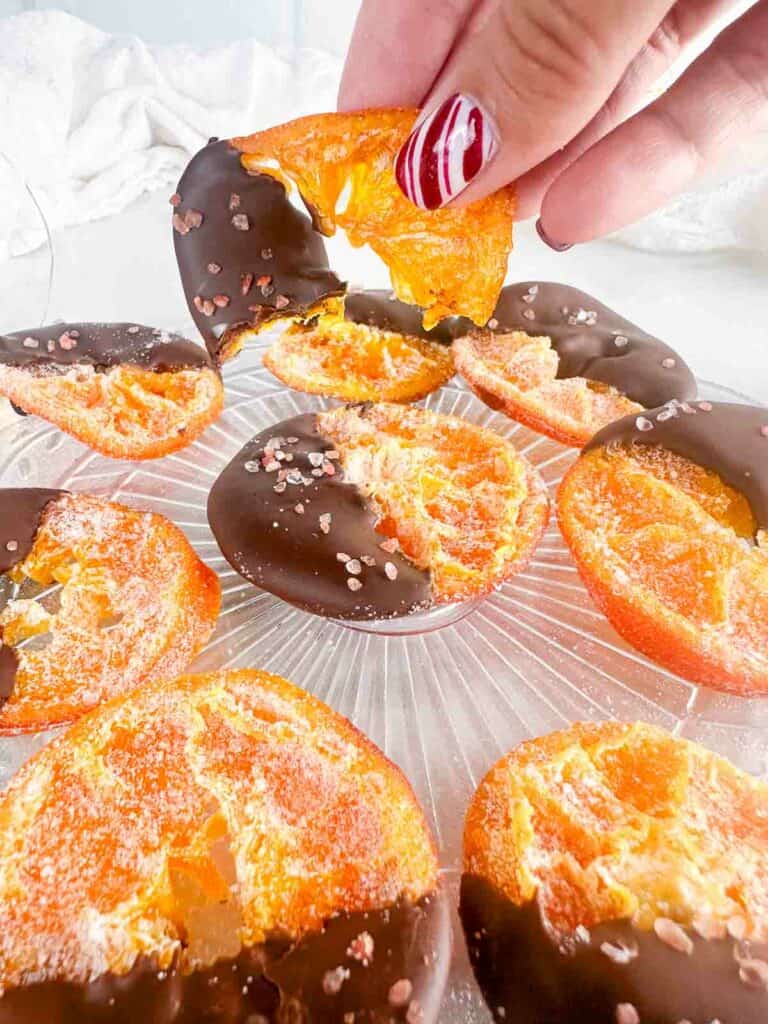 A half eaten chocolate dipped orange slice held above the others.