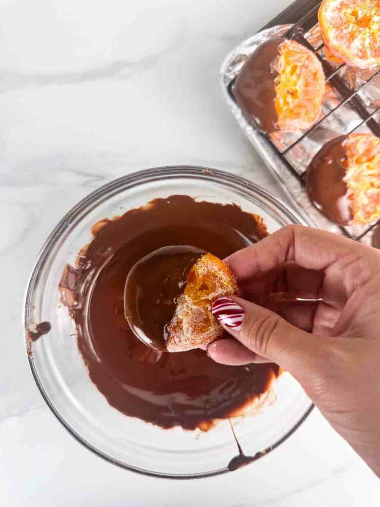 Dipping a candied orange in melted chocolate.