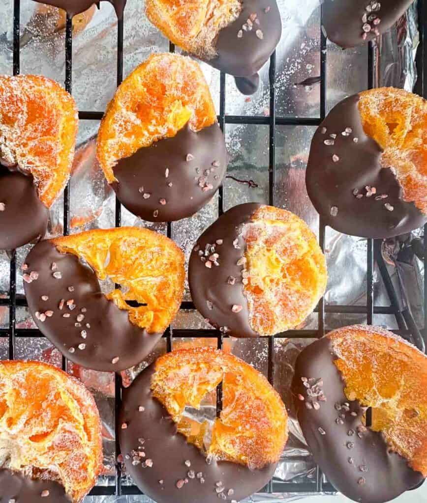 Drying chocolate dipped orange sices on a drying rack.