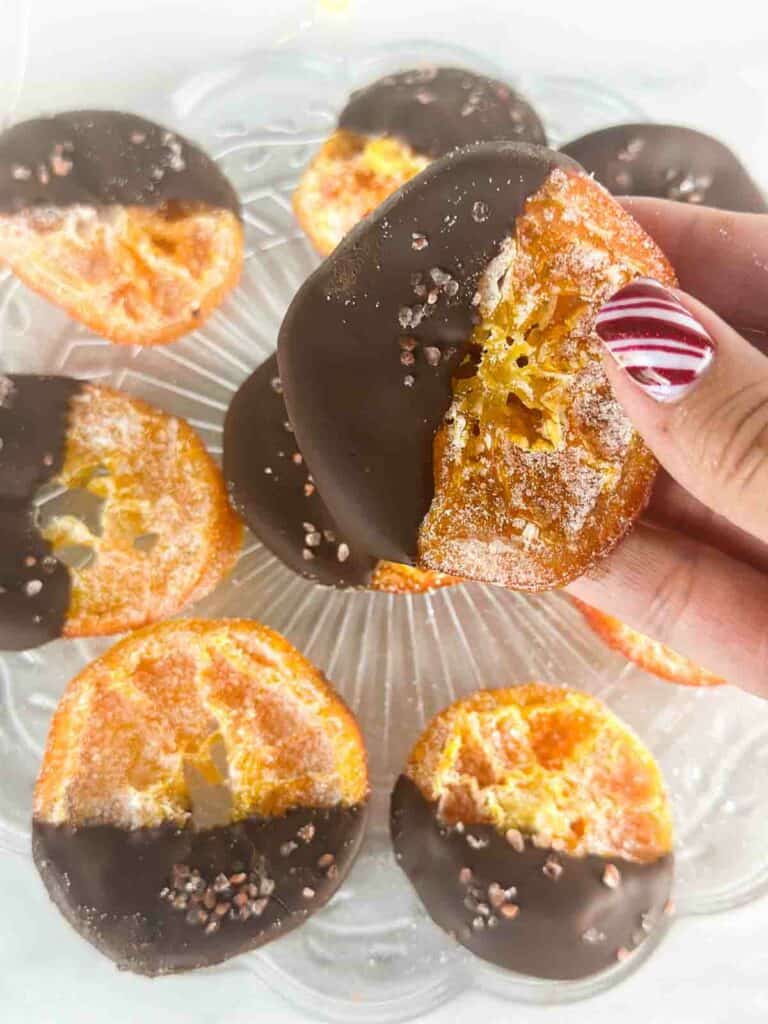 Chocolate dipped orange slice held up above others.