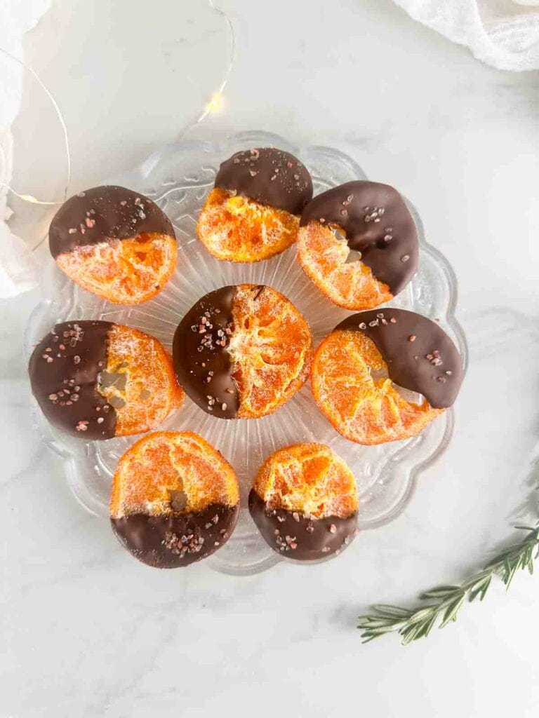 Chocolate dipped orange slices on a clear plate.