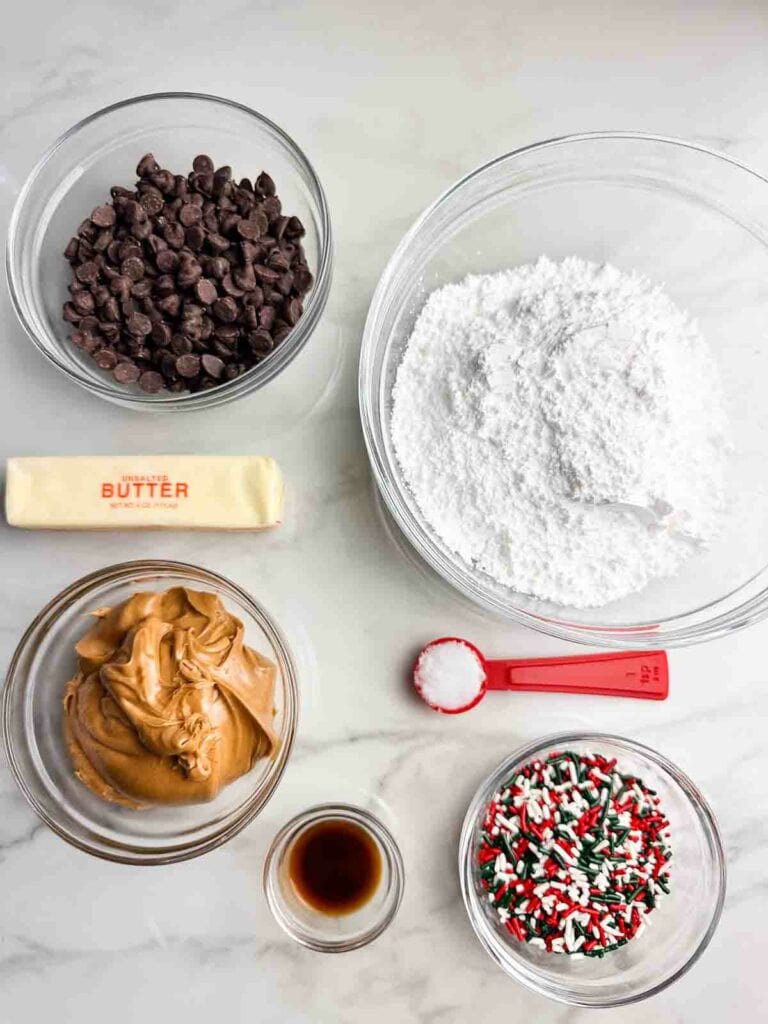 Ingredients for chocolate peanut butter balls recipe: chocolate chips, powdered sugar, butter, creamy peanut butter, coconut oil, vanilla, and sprinkles.