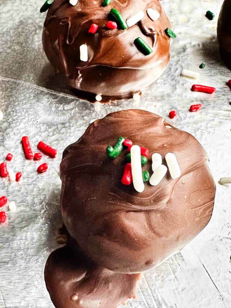 Chocolate covered peanut butter balls on a clear plate with sprinkles.