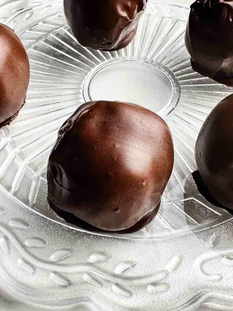 Chocolate covered peanut butter balls on a clear plate.