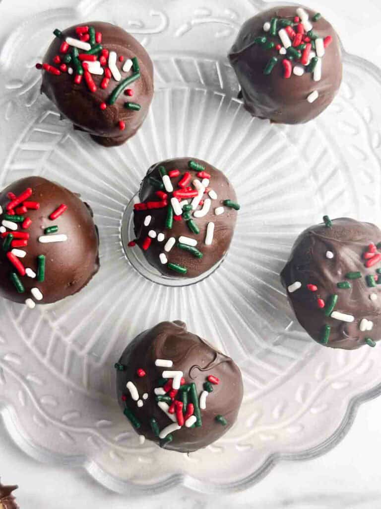 Chocolate covered peanut butter balls on a clear plate.