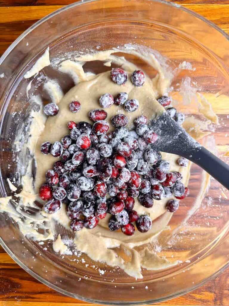 Folding in cranberries and walnuts to cranberry orange bread batter.