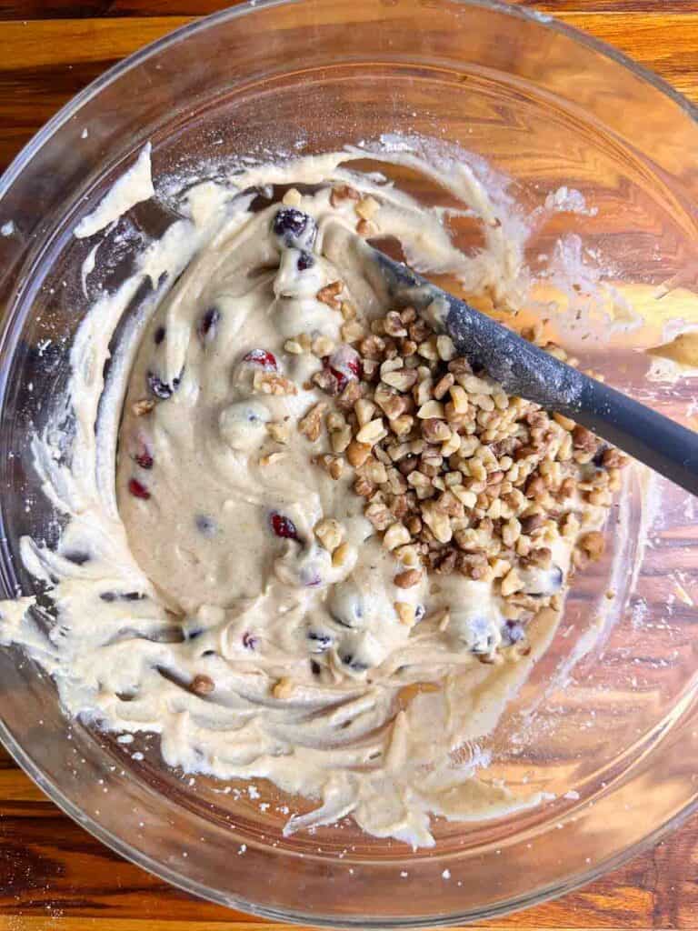 Folding in cranberries and walnuts to cranberry orange bread batter.