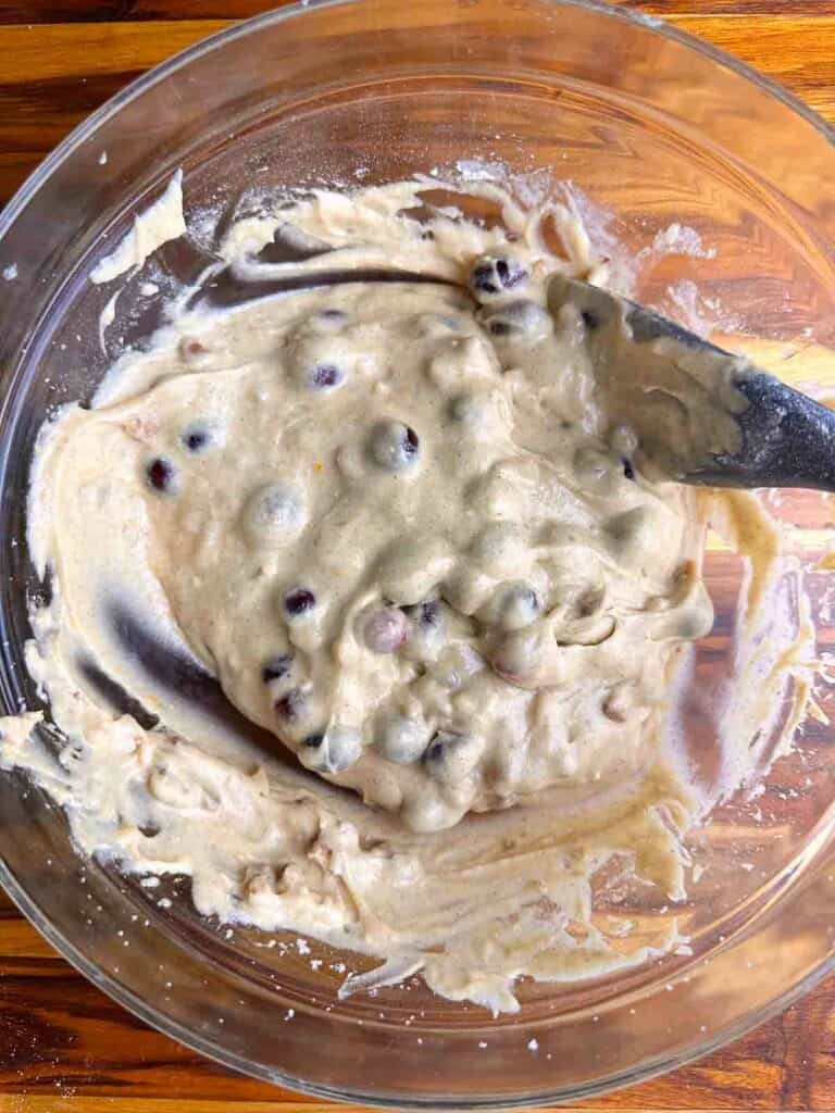 Folding in cranberries and walnuts to cranberry orange bread batter.