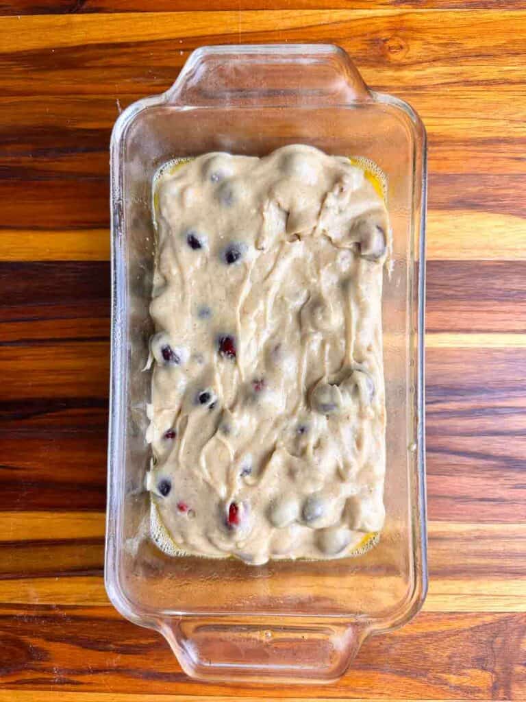 Batter for cranberry orange bread with walnuts in a greased bread pan.