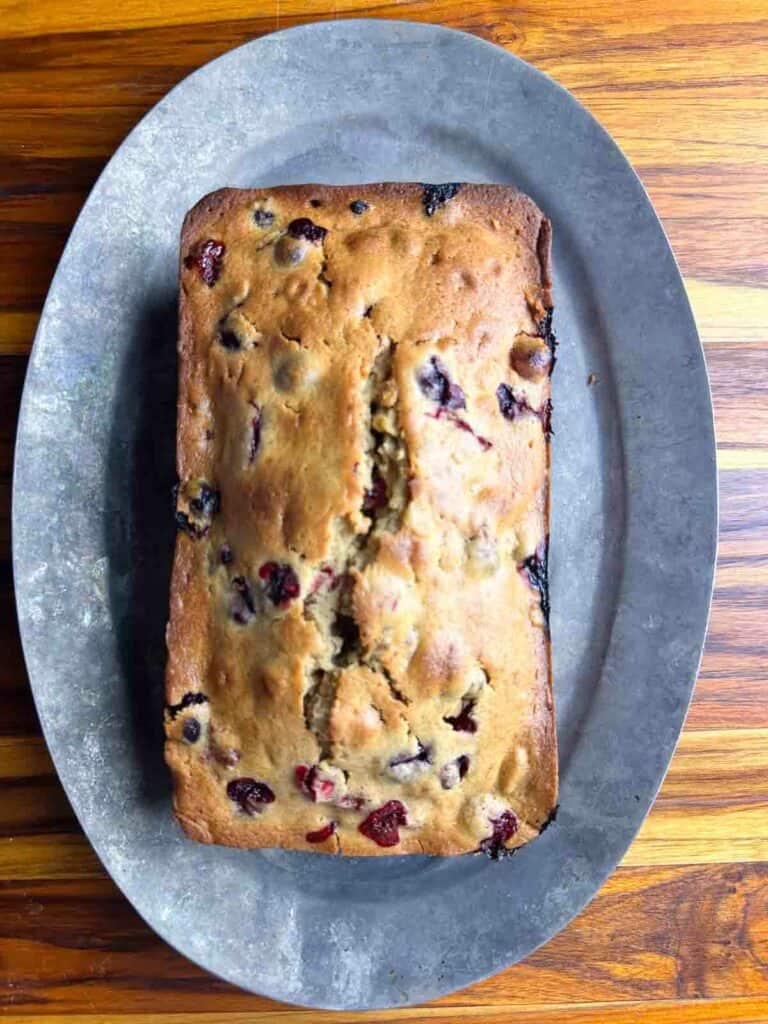 Fully baked cranberry orange bread with walnuts on a plate.