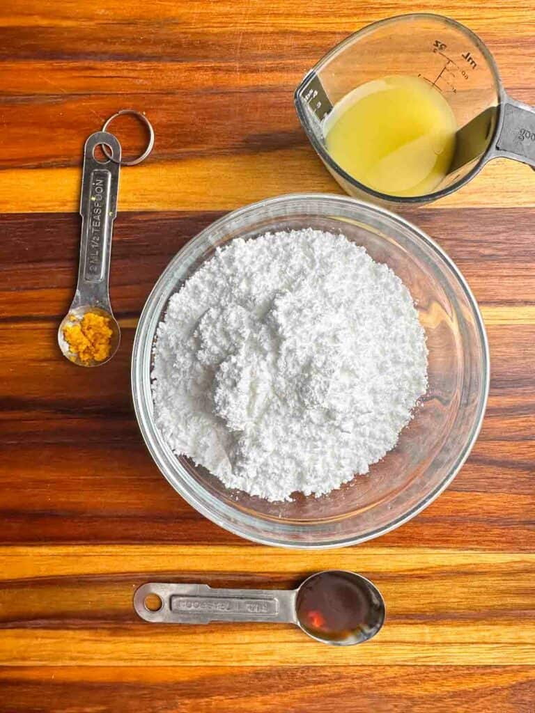 Ingredients for cranberry orange bread with walnuts glaze: orange zest, orange juice, powdered sugar, and vanilla extract.