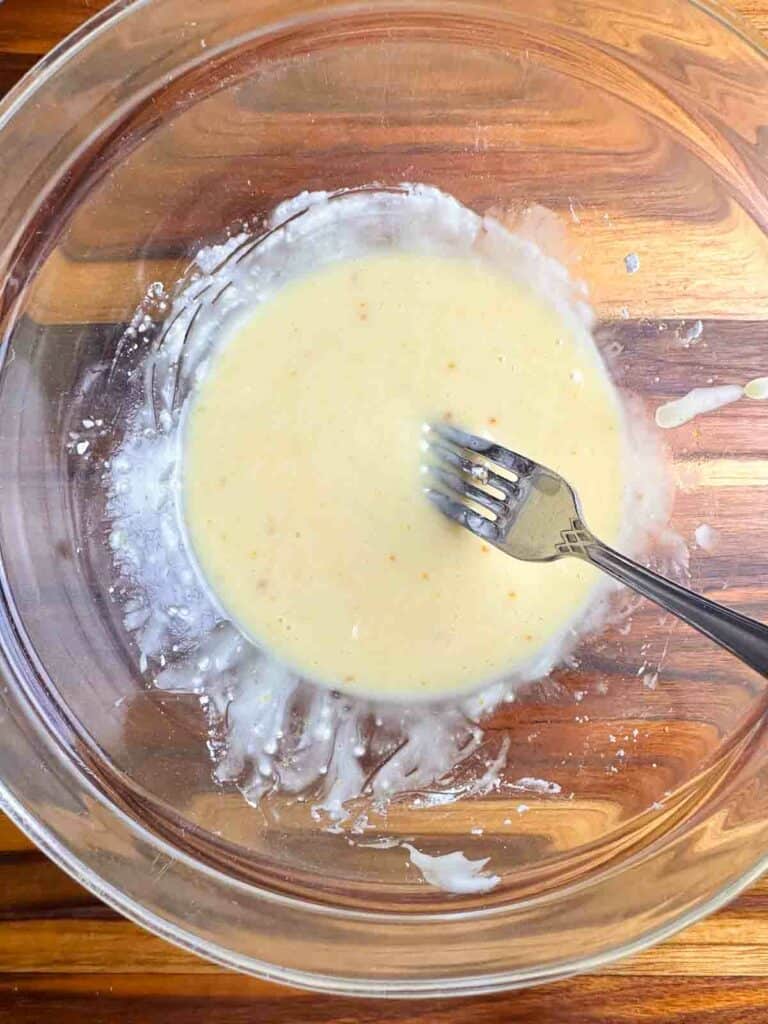Mixing an orange glaze for cranberry orange nut bread.