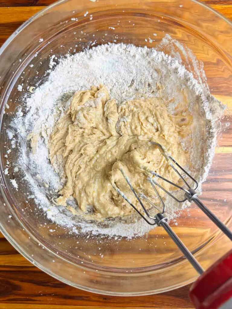 Mixing flour into the batter for cranberry orange bread with walnuts.