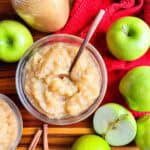 2 bowls and a mason jar of homemade applesauce in glass bowls with apples