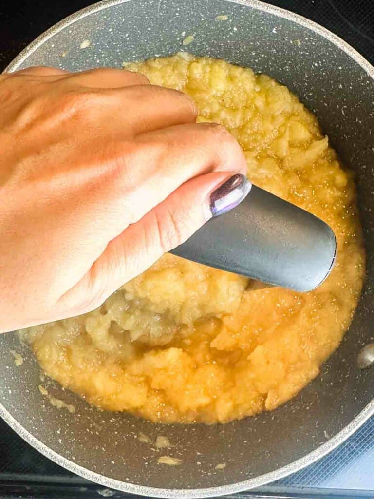 Mash the apples with a potato masher to make homemade applesauce