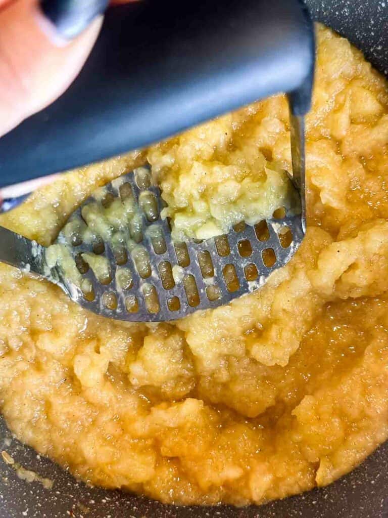 Mash the apples with a potato masher to make homemade applesauce