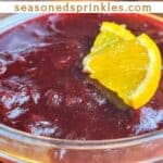Orange cranberry sauce with orange slices, cinnamon sticks, and cranberries. Text reads: orange cranberry sauce, seasonedsprinkles.com.