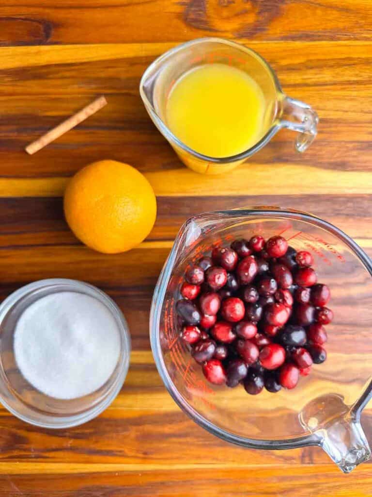 Ingredients for orange cranberry sauce recipe: CInnamon stick, orange juice, orange zest, granulated sugar, and cranberries.