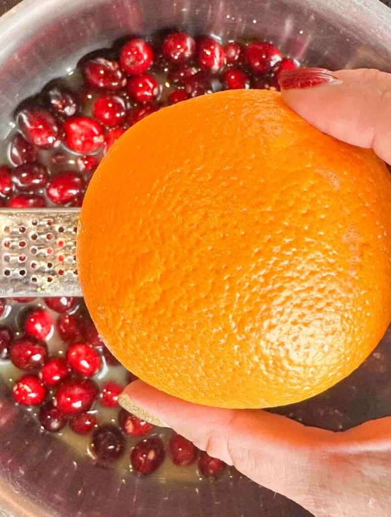 Zesting an orange into orange cranberry sauce.