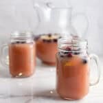 Christmas punch with cranberries and rosemary in mason jars and a pitcher.