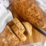 Partially sliced homemade bread with butter.