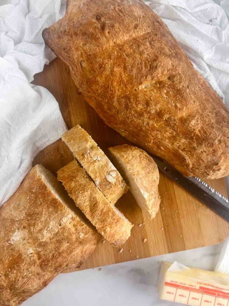 Partially sliced homemade bread with butter.