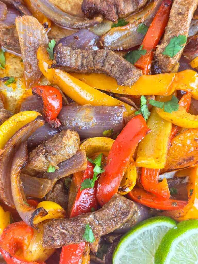 Close up of cooked sheet pan steak fajitas with onions and peppers.
