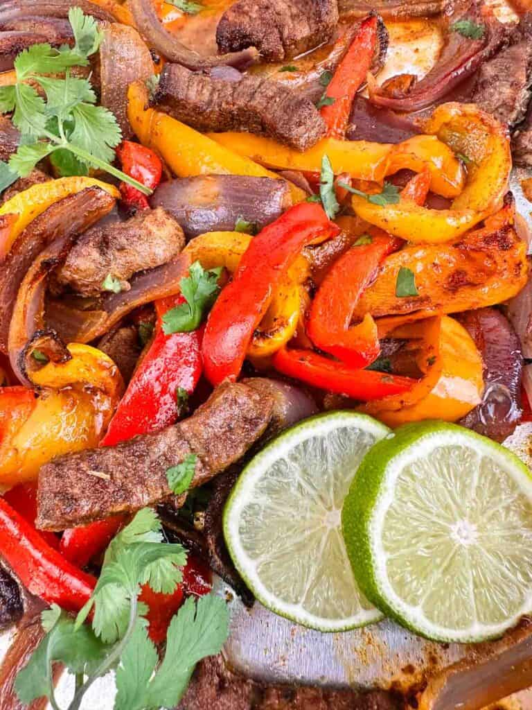 Close up of cooked sheet pan steak fajitas with onions and peppers.