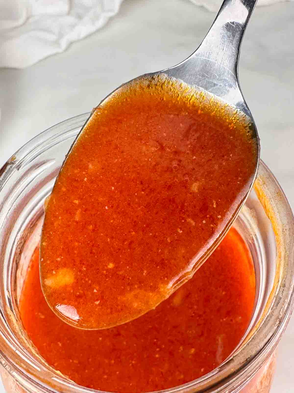 Spoon of buffalo wing sauce over the jar.