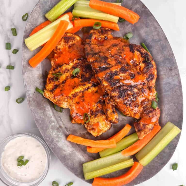 A platter of buffalo chicken chicken with carrots, celery, and blue cheese dressing