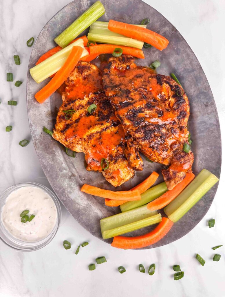 A platter of buffalo chicken chicken with carrots, celery, and blue cheese dressing