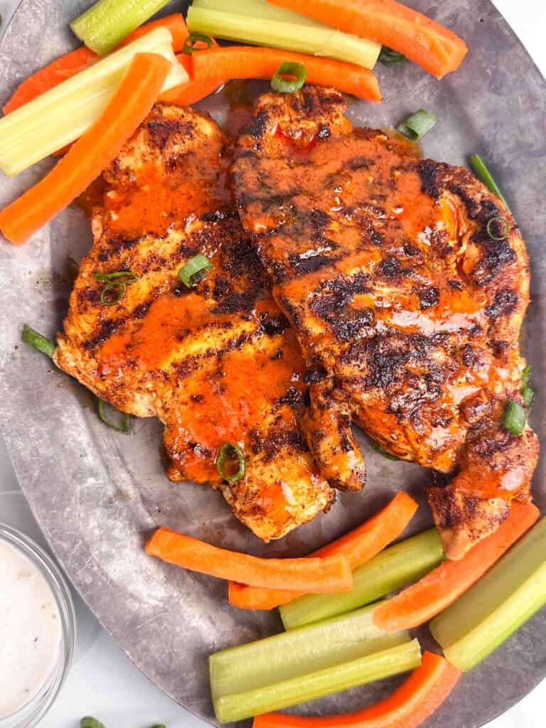 A platter of buffalo chicken chicken with carrots, celery, and blue cheese dressing