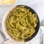 A bowl of pasta with creamy pesto sauce with parmesan cheese.