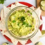 Guacamole recipe shown served on a plate with chips.