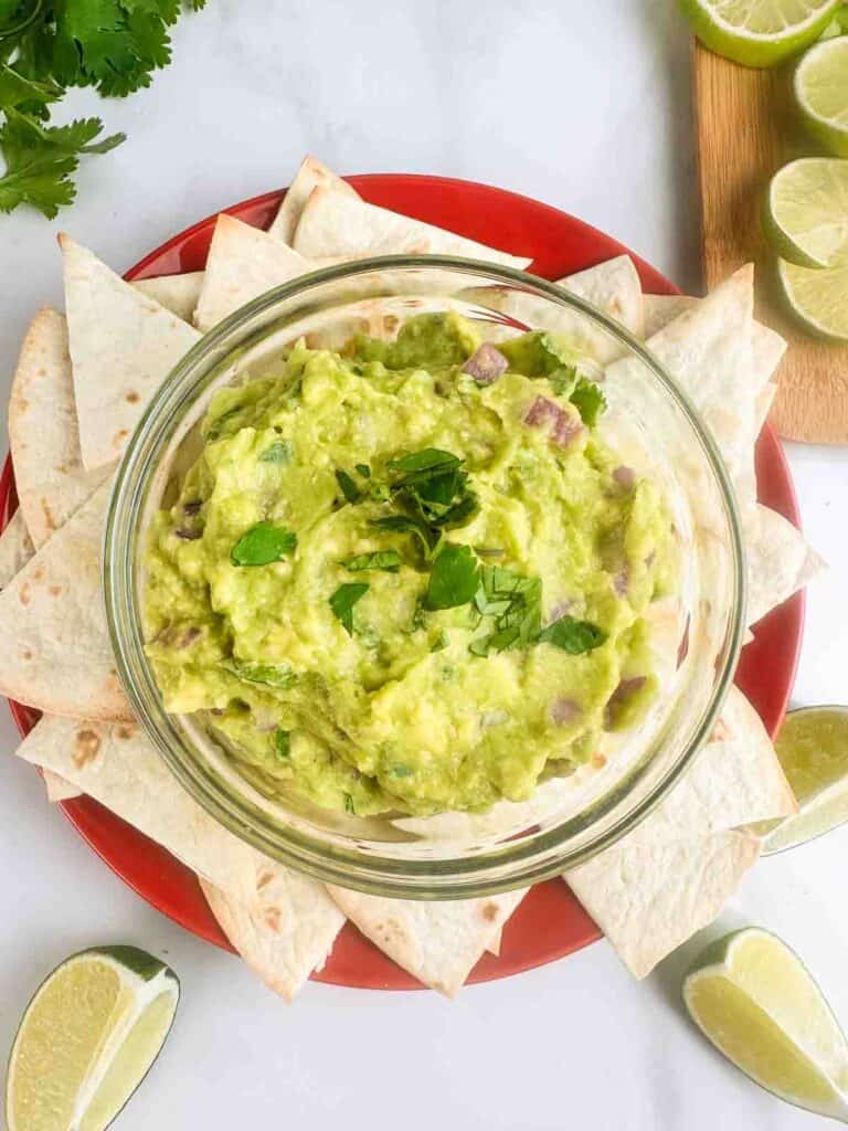 Guacamole recipe shown served on a plate with chips.