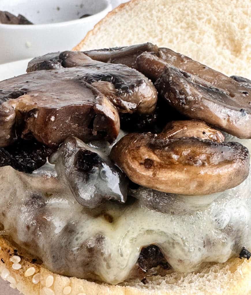 Suateed mushrooms on top of a cheese burger.